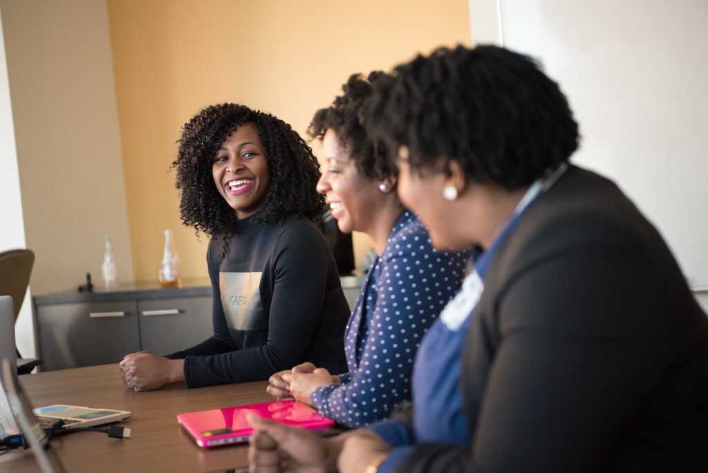 Three women sitting at table talking to one another and smiling
